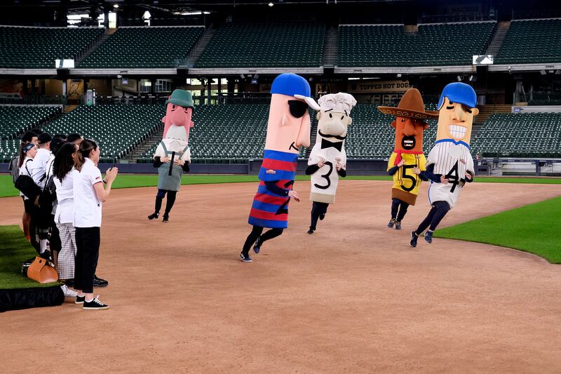 The contestants of Top Chef watch as characters run around a baseball field.