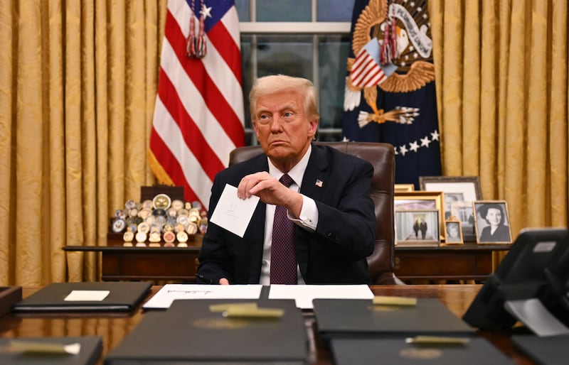 Donald Trump holds up Joe Biden's letter as he signs executive orders.