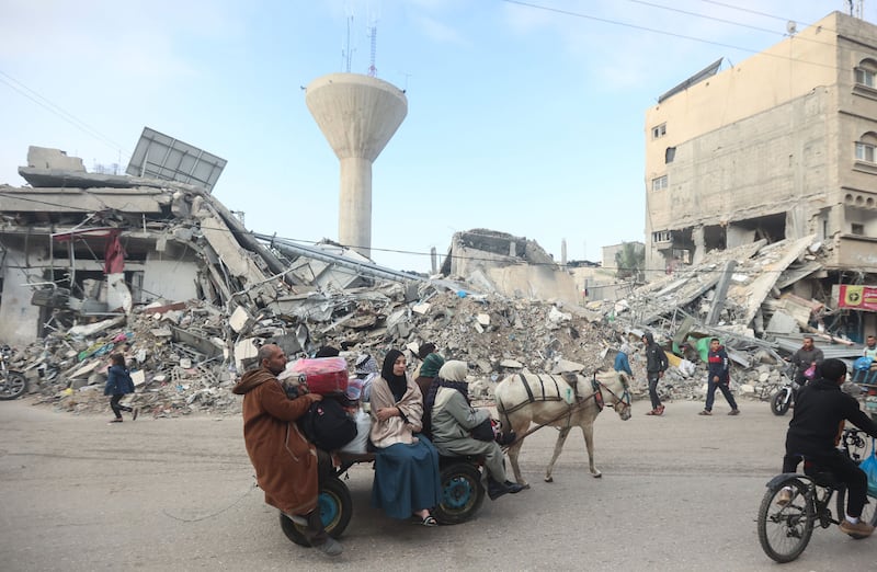 An image of Palestinians walking by rubble in Gaza.