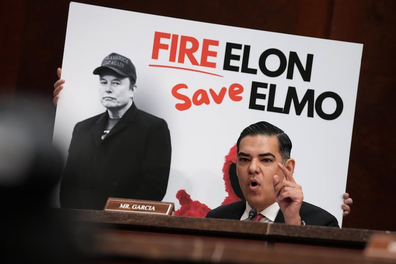 U.S. Rep. Robert Garcia (D-CA) speaks in front of poster of Tesla and SpaceX CEO Elon Musk.