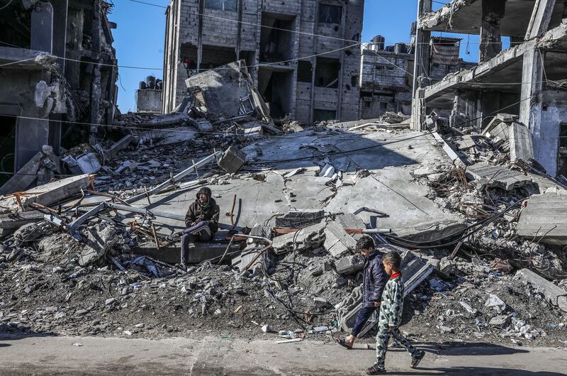 Palestinian children walk among collapsed buildings as daily life continues under Israeli attacks in Rafah on February 05, 2024.