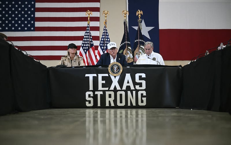 President Donald Trump and First Lady Melania Trump sit with Texas governor Greg Abbott (R) as they attend a roundtable meeting with local officials and first responders in Kerrville, Texas, on July 11, 2025.