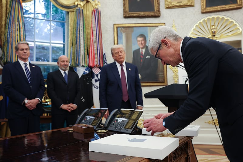 WASHINGTON, DC - AUGUST 06: Apple CEO Tim Cook (R) presents U.S. President Donald Trump with an engraved glass disc during an event in the Oval Office of the White House on August 6, 2025 in Washington, DC. Apple Inc. announced a $100 billion investment in manufacturing facilities in the U.S., on top of an announcement in February committing over the next four years to a $500 billion investment in the U.S. economy and the addition of 20,000 new jobs. (Photo by Win McNamee/Getty Images)
