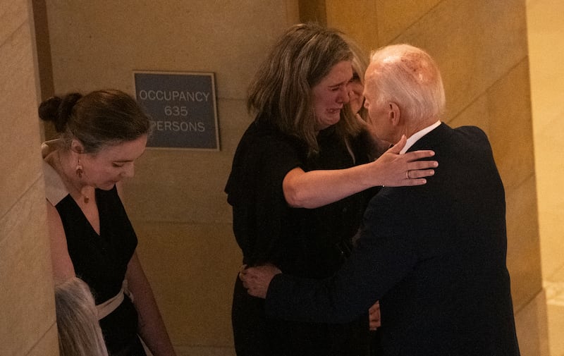 Former President Joe Biden is embraced after viewing the caskets.