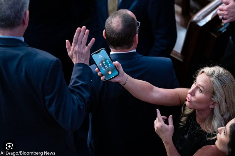 Marjorie Taylor Greene tries to hand a cell phone to a member of Congress during the Speaker vote.