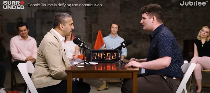 Connor (right) and Mehdi Hasas debate on a table as part of Surrounded episode.