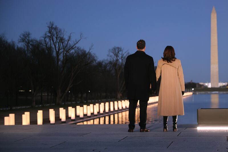 Douglas Emhoff (L) and U.S. Vice President-elect Kamala Harris look down the National Mall as lamps are lit to honor the nearly 400,000 American victims of the coronavirus pandemic at the Lincoln Memorial Reflecting Pool January 19, 2021.