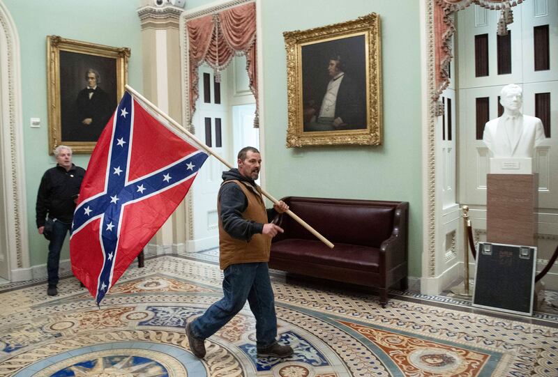 A supporter of US President Donald Trump carries a Confederate flag as he protests in the US Capitol Rotunda on January 6, 2021, in Washington, DC.