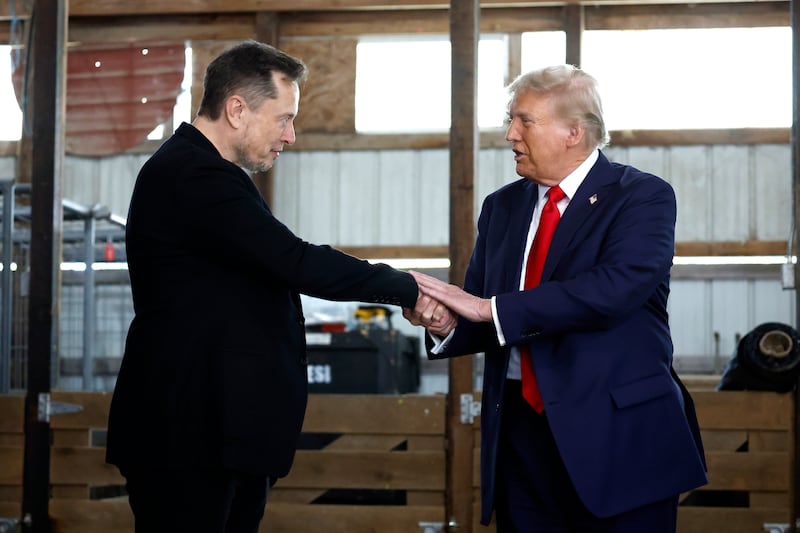 Elon Musk (L) shakes hands with President Donald Trump back stage during a campaign rally at the Butler Farm Show grounds on October 05, 2024 in Butler, Pennsylvania.