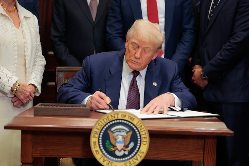 Donald Trump signing an executive order in the Oval Office.