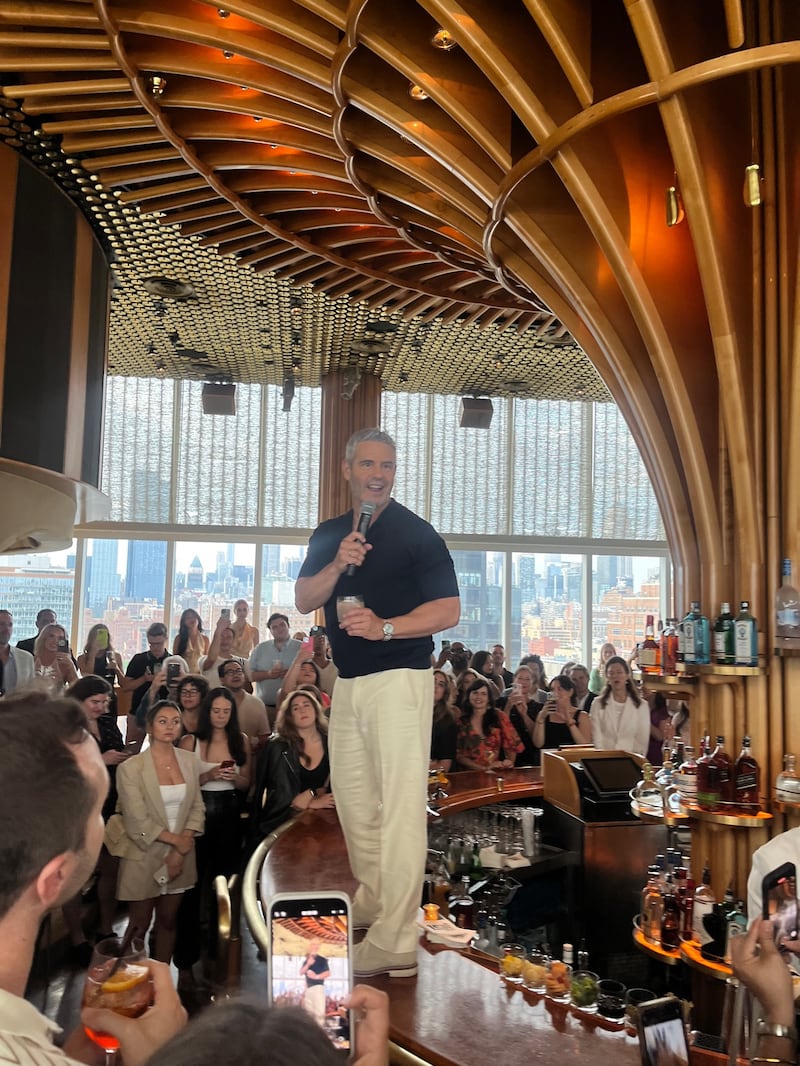 Andy Cohen standing on bar speaking to crowd at Watch What Happens Live