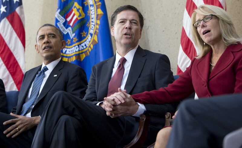 President Barack Obama sings "God Bless America" alongside new FBI Director James Comey (C) and Comey's wife, Patrice Failor (R), during an installation ceremony at Federal Bureau of Investigation Headquarters in Washington, DC, October 28, 2013.