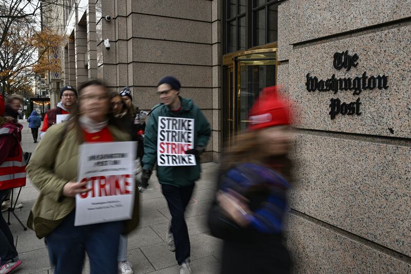 Washington Post employees carry signs in protest outside of their newsroom.