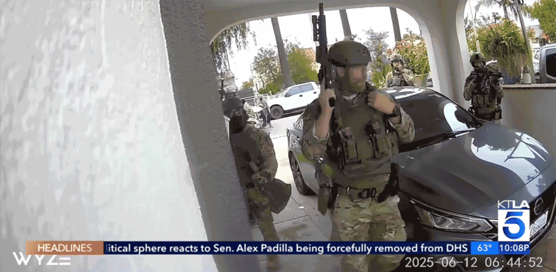 A masked U.S. Immigration and Customs Enforcement agent turns an outdoor camera away during a raid in Huntington Park, California.