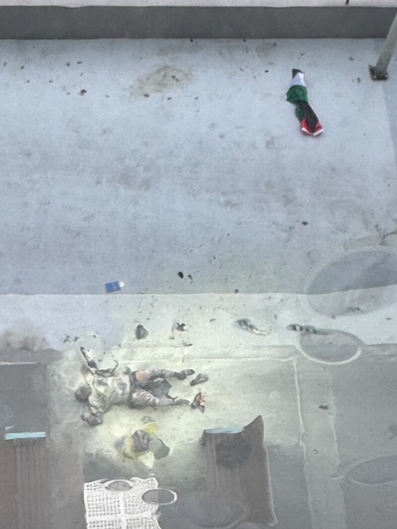 A woman lays on the ground near a Palestine flag after setting herself ablaze.