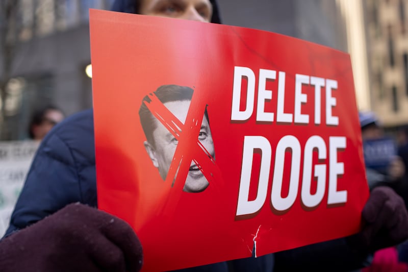 Protestor holds a sign reading "delete Doge" during protests against Elon Musk's federal cost-cutting.