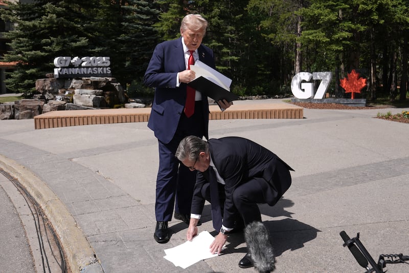 British Prime Minister Keir Starmer picks up US-UK trade deal papers dropped by President Donald Trump as they speak to reporters during the G7 Summit in Kananaskis, Alberta, Canada on June 16, 2025.