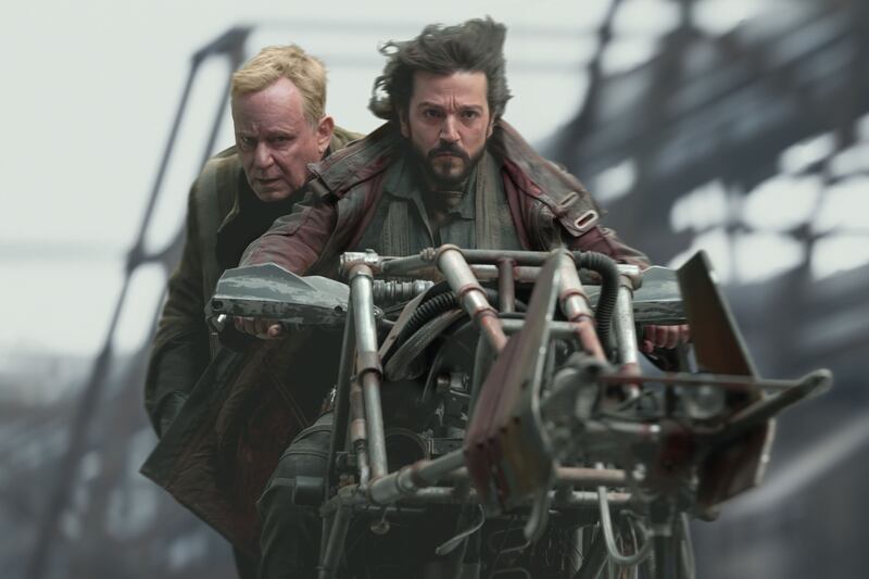 Luthen Rael rides on the back of a rider with Cassian Andor in a still from “Andor”