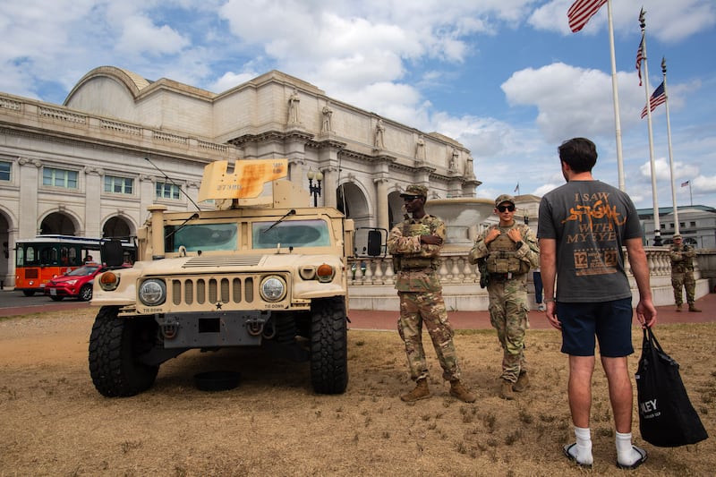 A young man talks with members of the U.S. National Guard at Columbus Circle. National Guard troops also patrol near Union Station following President Donald Trump's announcement to place the D.C. Metropolitan Police Department under federal control and deploy federal officers and the National Guard to help prevent crime in the capital.