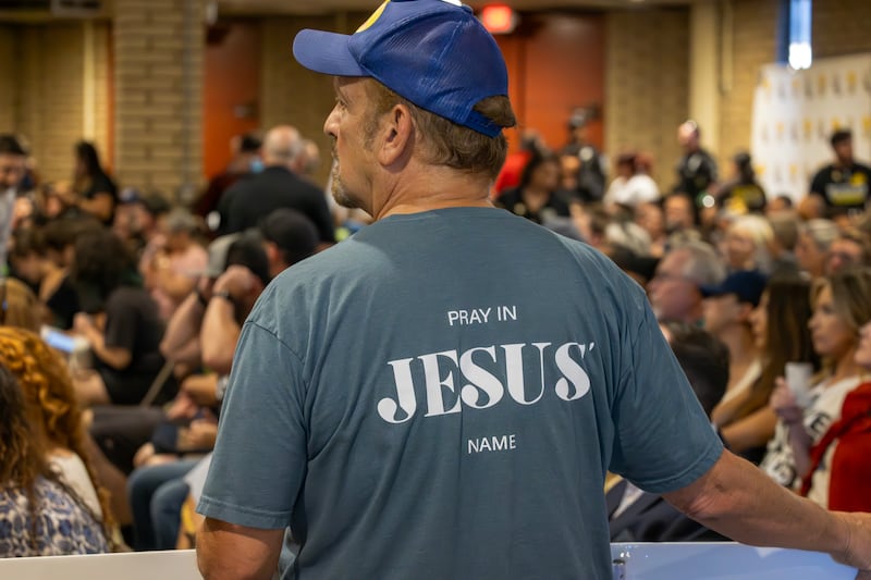 A man wears an evangelical t-shirt and holds a banner in support of a policy that the Chino Valley school board is meeting to vote on which would require school staff to \"out\" students to their parents.