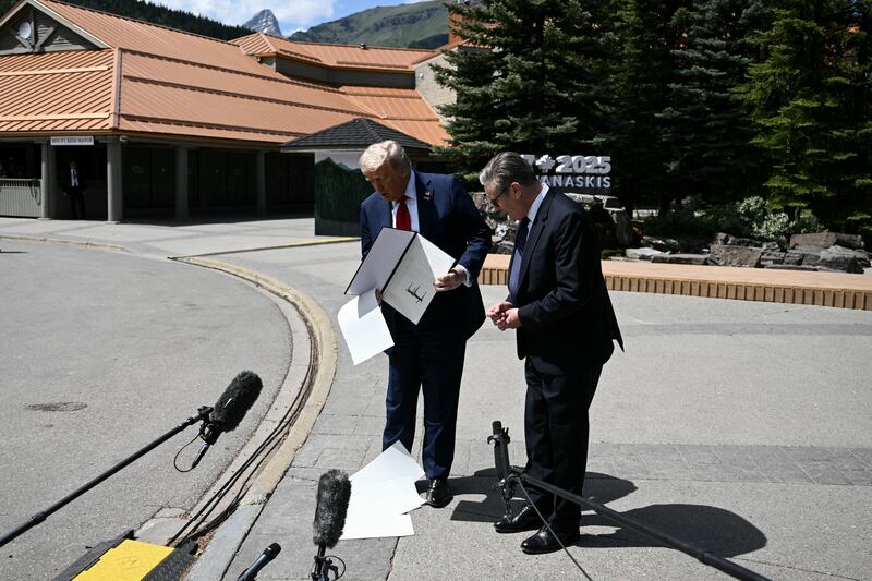 President Donald Trump dropping pages from the US-UK trade deal document while standing next to British Prime Minister Keir Starmer in Kananaskis, Alberta, Canada on June 16, 2025.