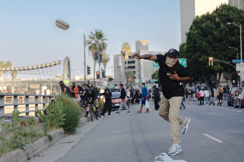 LOS ANGELES, CALIFORNIA - JUNE 8: A protester throws a rock at police who were staging on the 101 freeway during clashes on June 8, 2025 in Downtown Los Angeles, California. The clashes come after ICE raids swept throughout the city over the weekend. (Photo by Jim Vondruska/Getty Images)