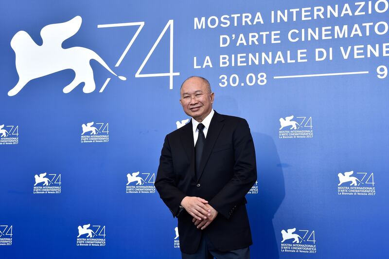 John Woo standing in front of a Venice step and repeat.