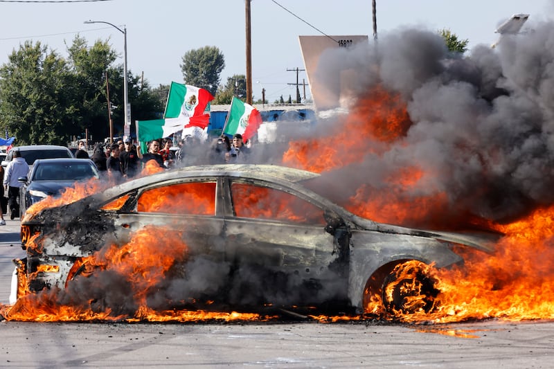 A car burns in the middle of the intersection of Atlantic Ave. and E Alondra Blvd. during ICE protests on Saturday, June 7, 2025 in Los Angeles.