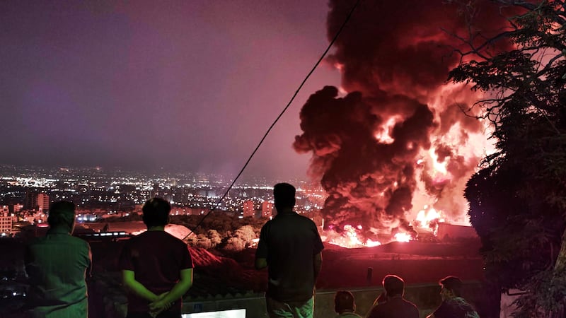 People observe fire and smoke from an Israeli attack on the Shahran oil depot on June 15 in Tehran. Iran's foreign minister said the country would respond "decisively and proportionally" to a wave of attacks that Israel launched beginning in the early hours of June 13. The attacks targeted multiple military, scientific and residential locations, as well as senior government officials.