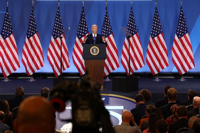 Joe Biden seen at a lectern surrounded by flags