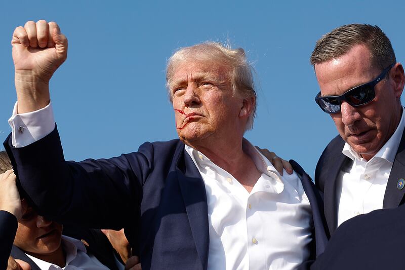 Donald Trump pumps his fist as he is rushed offstage by U.S. Secret Service agents after being grazed by a bullet in an assassination attempt.