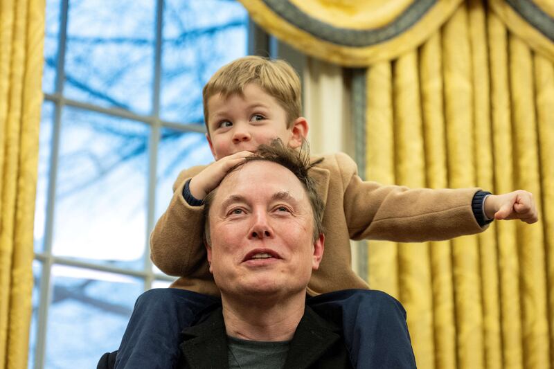 Elon Musk carries his son X Æ A-Xii on his shoulders while speaking in the Oval Office of the White House in Washington, DC, on February 11, 2025. Tech billionaire Elon Musk, who has been tapped by President Donald Trump to lead federal cost-cutting efforts, said the United States would go "bankrupt" without budget cuts. Musk leads the efforts under the newly created Department of Government Efficiency (DOGE), and was speaking at the White House with Trump, who has in recent weeks unleashed a flurry of orders aimed at slashing federal spending. (Photo by Jim WATSON / AFP) (Photo by JIM WATSON/AFP via Getty Images)
