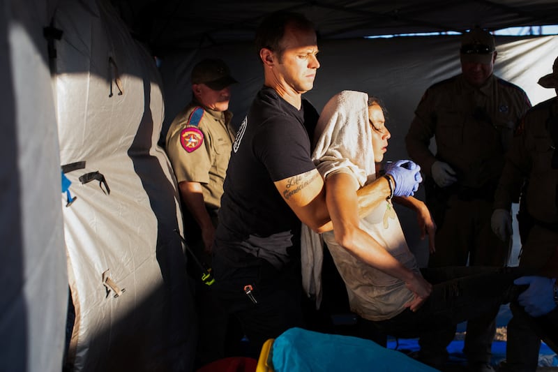 EMT William Dorsey lifts a migrant woman suffering from heat exhaustion onto a stretcher in the border community of Eagle Pass, Texas.