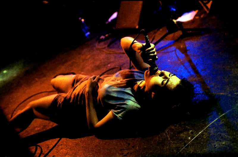 Kathleen Hanna lays on her back and sings.