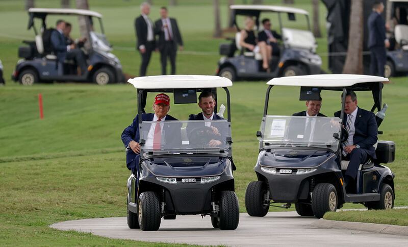 President Donald Trump and his son, Eric Trump, drive in a golf cart after he arrived on Marine One at the LIV Golf tournament being held at his Trump National Doral Golf Club on April 03, 2025 in Doral, Florida.