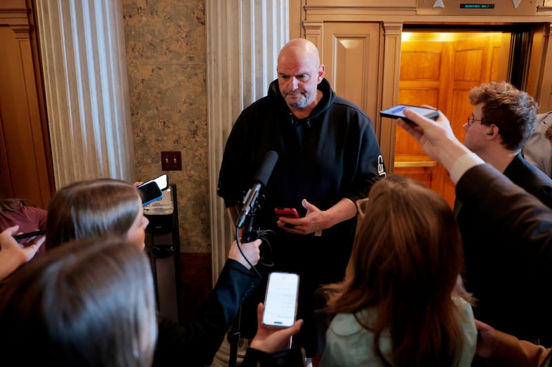 Senator John Fetterman, pictured speaking to reporters on March 13,  still uses his phone to transcribe conversations in real time to help with auditory processing issues stemming from a stroke in 2022.