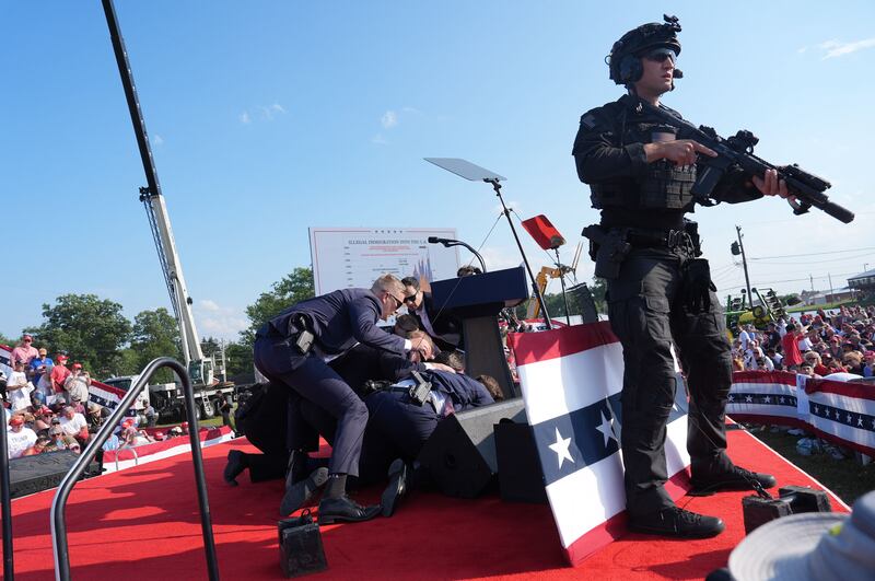 Secret service agents cover former president Donald Trump during a campaign rally