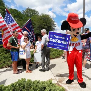 A person wearing a mouse costume and holding a Ron DeSantis poster stands with supporters of Florida’s Republican-backed “Don’t Say Gay” bill in Orlando, Florida, April 16, 2022.