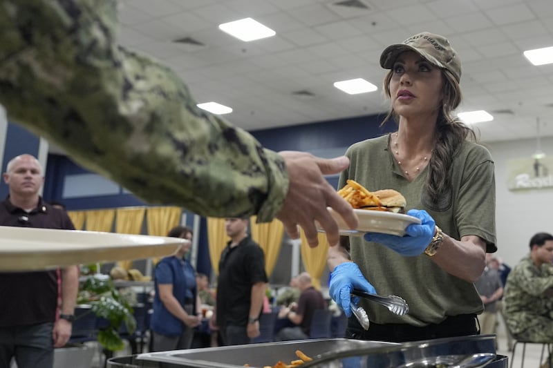Kristi Noem helps served food to sailors and coast guardsmen in Bahrain.