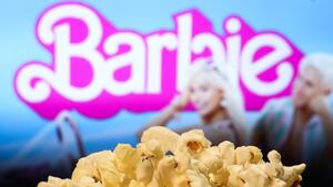 A popcorn and Barbie movie website displayed on a screen in the background