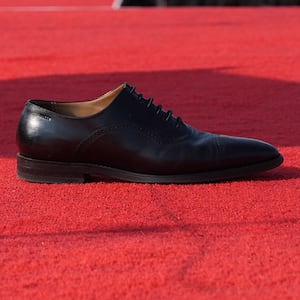 Donald Trump's abandoned black polished Oxford shoe, on a red carpet