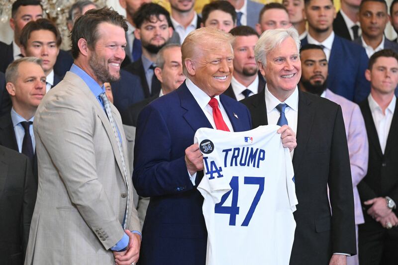 Donald Trump holds up a jersey alongside pitcher Clayton Kershaw (L) and team owner Mark Walter (R) during an event honoring the 2024 World Series champions Los Angeles Dodgers in the East Room of the White House.