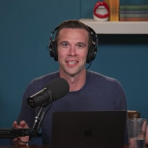 Pod Save America host Jon Favreau speaks into a microphone.
