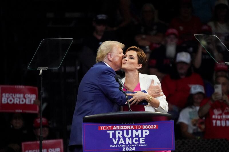 Republican presidential nominee Donald Trump and Kari Lake embrace during a campaign rally in Prescott Valley, Arizona on October 13, 2024.