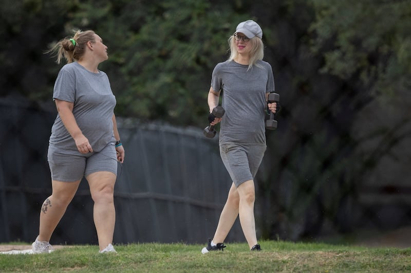 Theranos founder Elizabeth Holmes, right, carries hand weights while walking on the track at Federal Prison Camp Bryan over the weekend.