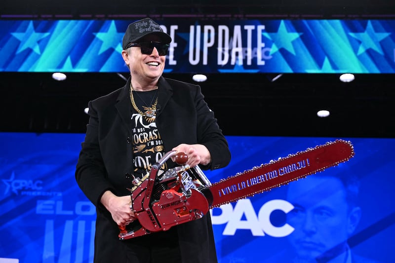 Elon Musk holds a chainsaw reading "Long live freedom, damn it" during the annual Conservative Political Action Conference.