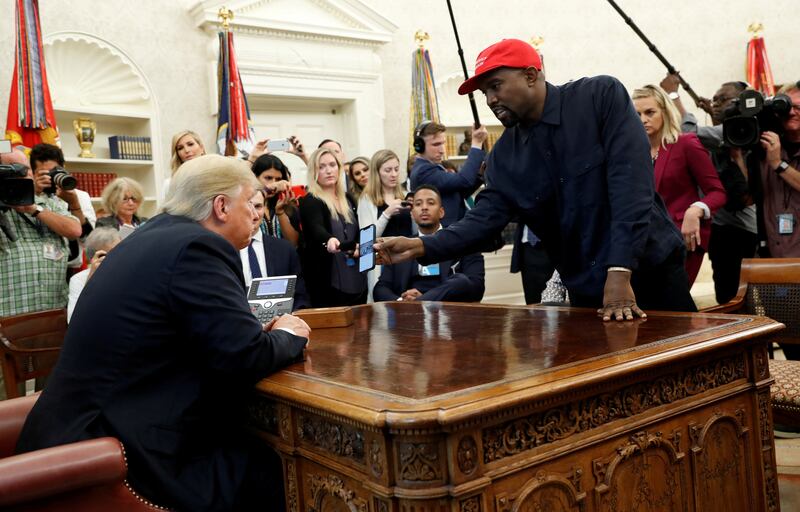 Kanye West shows President Donald Trump his mobile phone during a meeting in the Oval Office
