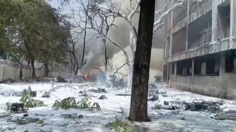Smoke rises near a damaged building and trees after an Air India plane crashed in Ahmedabad, India.