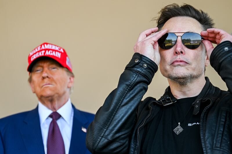 Musk puts on sunglasses with Donald Trump behind him in a MAGA hat