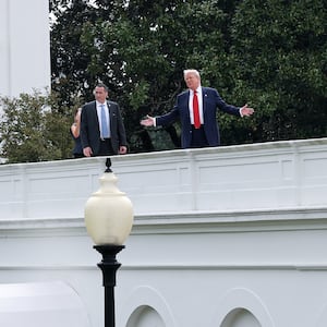 U.S. President Donald Trump gestures while answering questions from reporters as he tours the roof of the West Wing of the White House